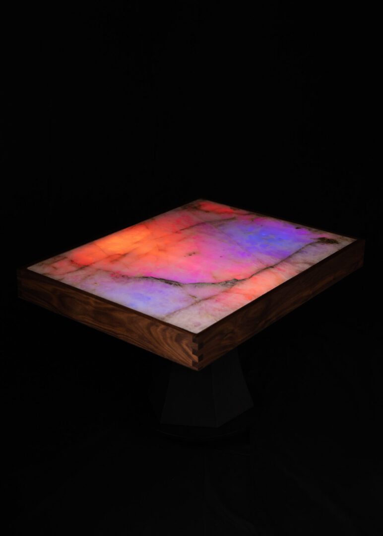 A glowing, multicolored rectangular slab on a dark pedestal.