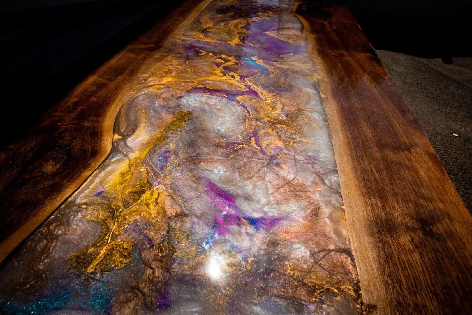 Close-up of a polished wooden surface with colorful resin inlays.