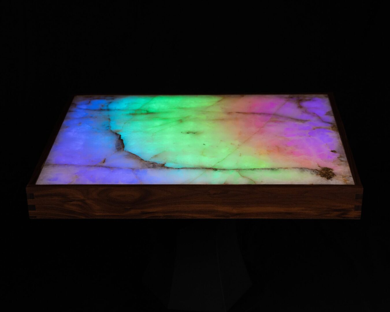 A glowing rectangular panel with multicolored light and wooden frame.
