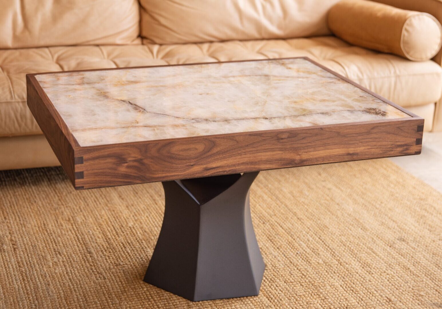 Wooden pedestal table with a thick slab top near beige sofa.